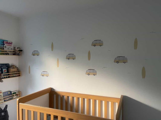 Nursery room with wooden crib and wall stickers of cars and surfboards.